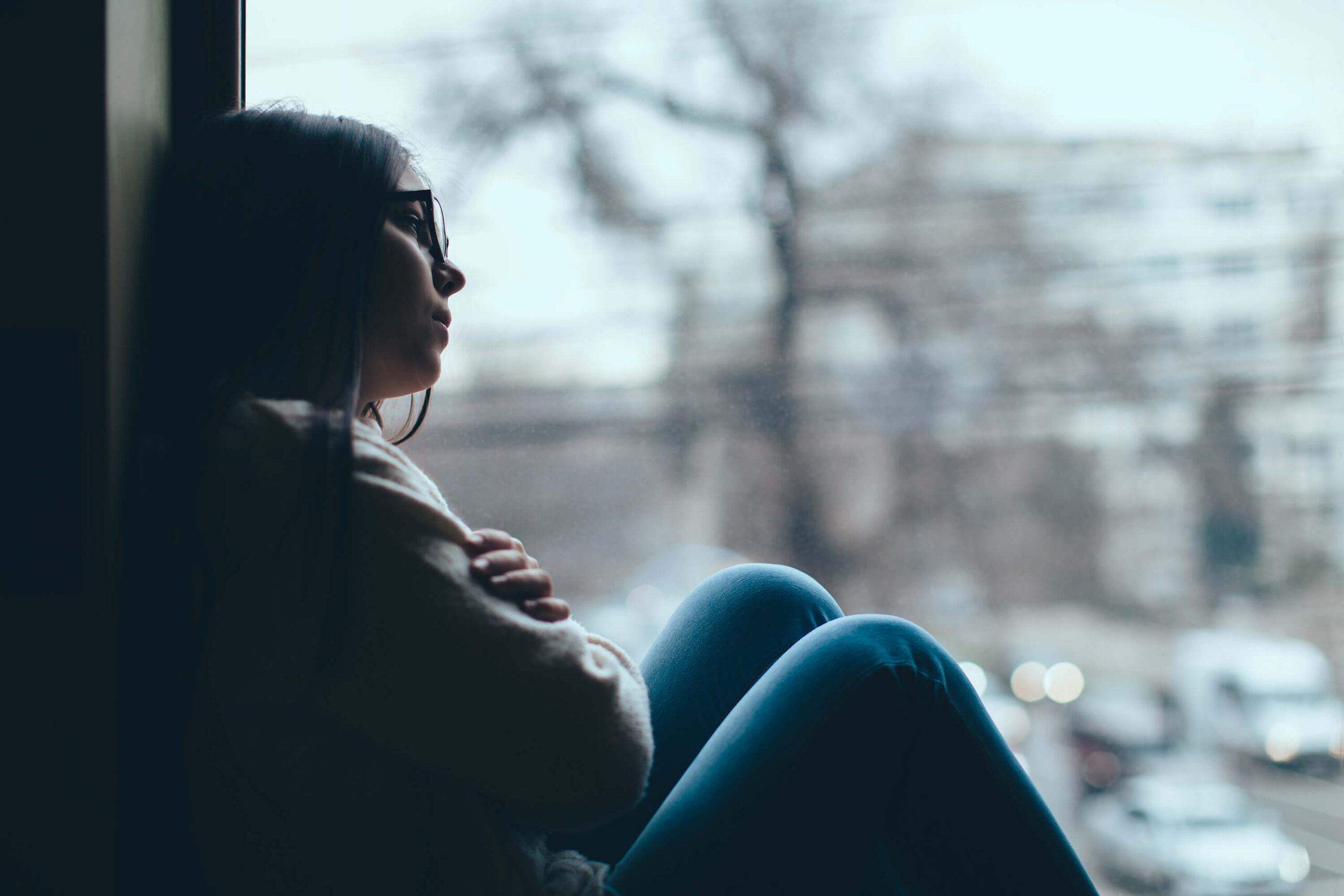 Picture shows a teen looking out a cold window at a crisis point.
