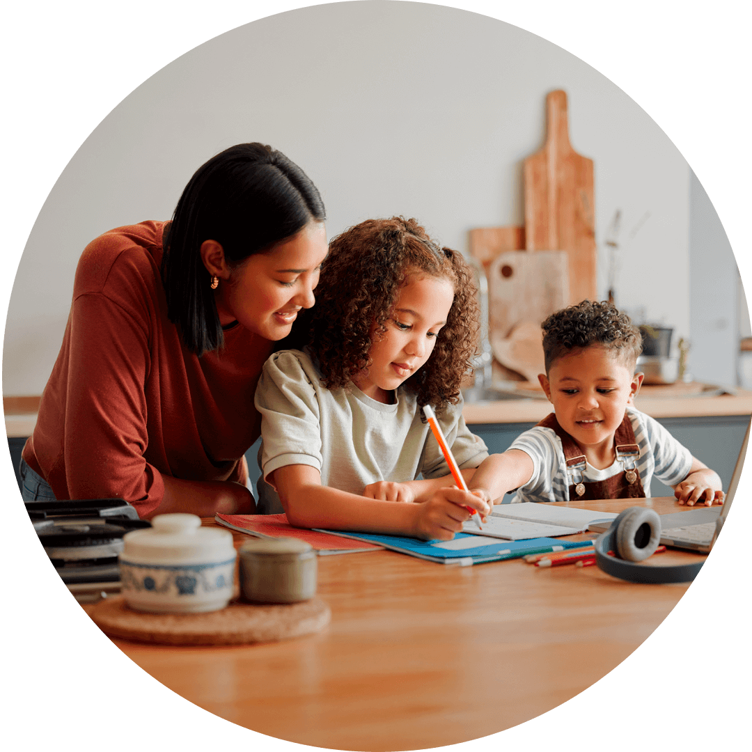 A mother figure helps two young children with their homework at a kitchen table, fostering connection and support.