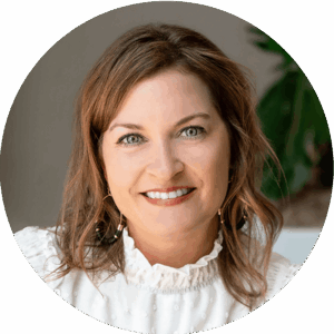 Angela Roberson smiling warmly in a professional headshot, wearing a white blouse with ruffled detail and earrings, against a soft indoor background.