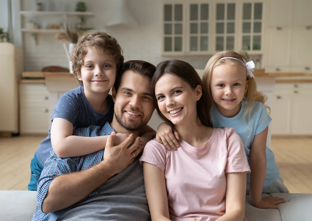 Adoptive family sitting together on a couch, smiling and connected in a bright, welcoming home.