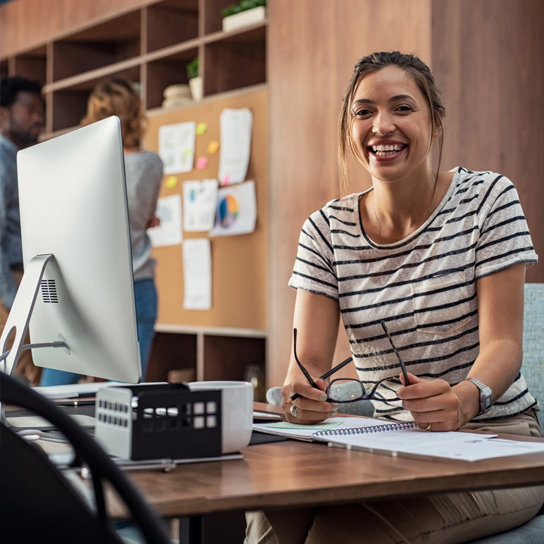 Professional working at a desk with a computer and documents in an office setting, representing organizational support solutions